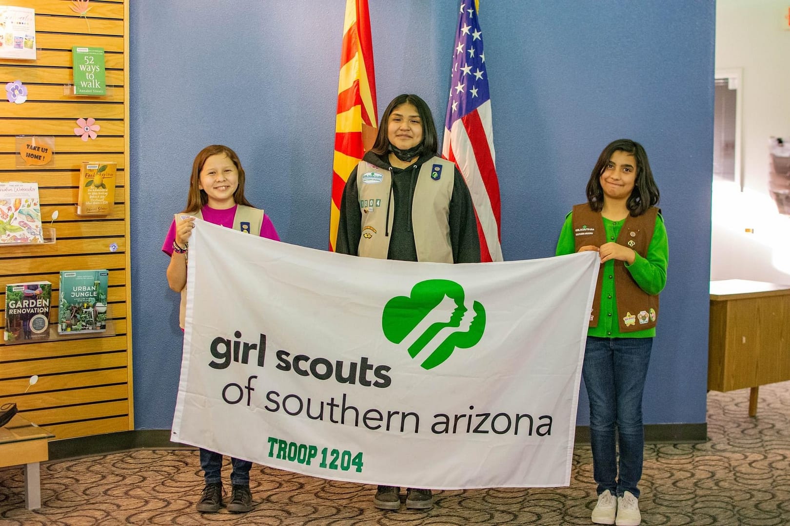 Three Girl Scouts Holding a Girl Scouts of Southern Arizona Troop 1204