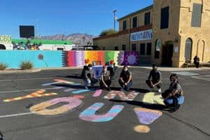 Youth Next to Colorful Chalk Drawing That Reads "Think You!"